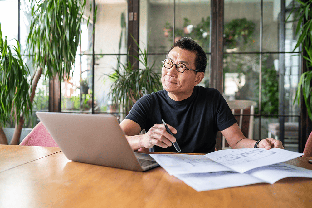 mature asian man with laptop thinking