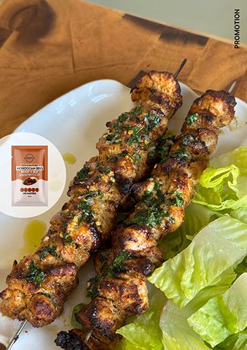 Moroccan chicken skewers on a plate with salad, with Mingle seasoning overlay