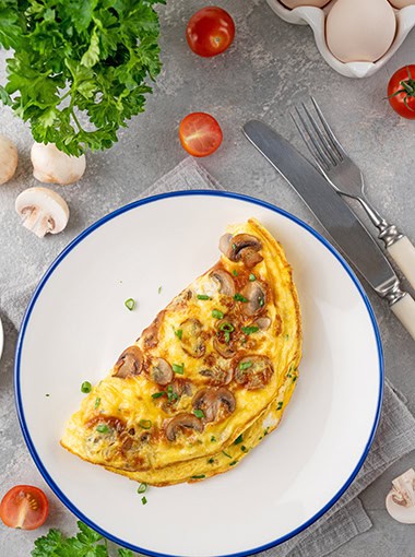 Omelet with fried mushrooms and fresh herbs in a plate