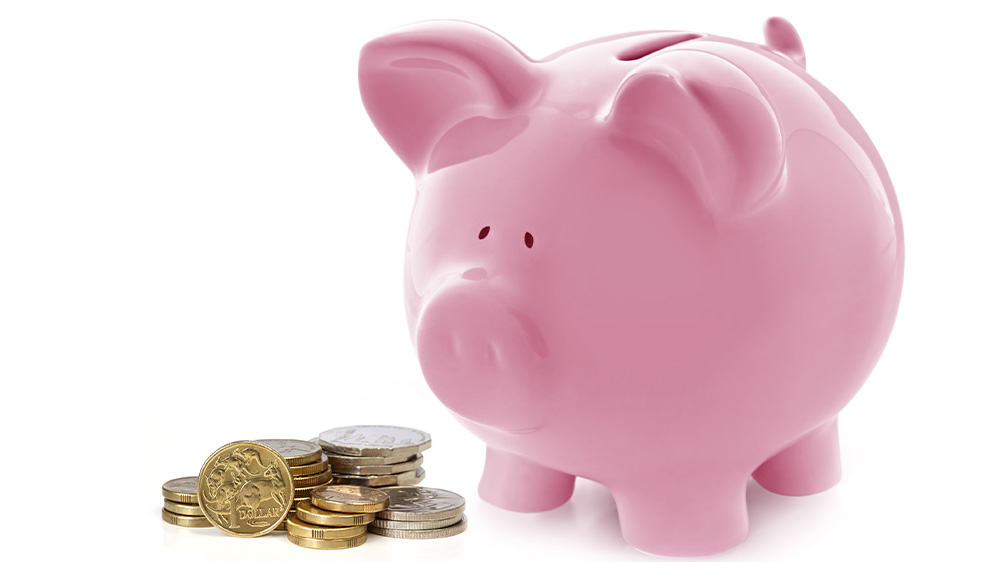 Pink piggy bank next to a pile of coins