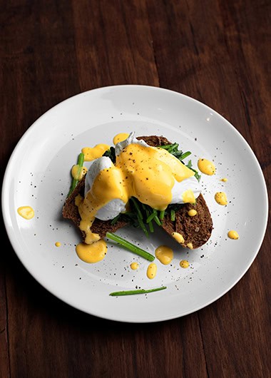 Eggs Benedict breakfast with toast, spinach and top with hollandaise sauce