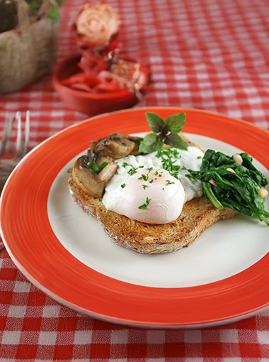 Poached egg breakfast with blanched spinach and pine nuts with mushrooms and shallots.