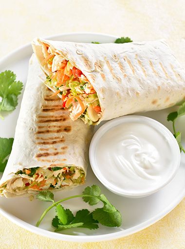 Chicken and salad wraps on a plate with dipping sauce
