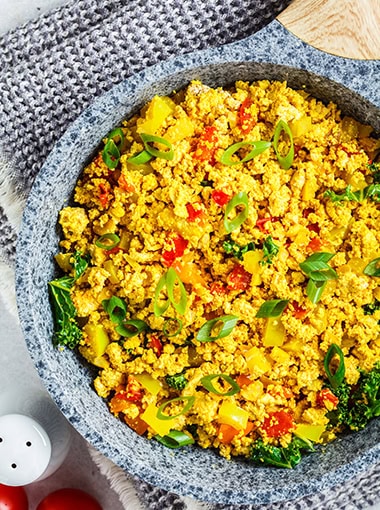 Scramble tofu with vegetables in a pan.