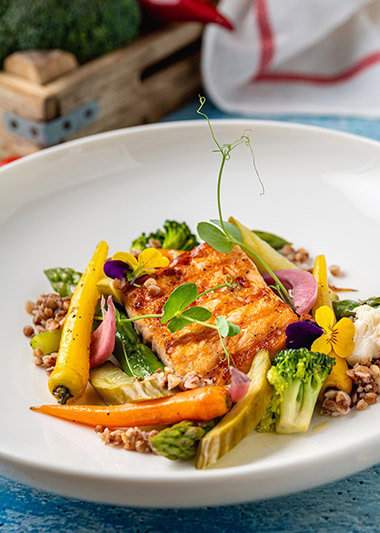 Seared salmon fillet served with grains and seasonal vegetables