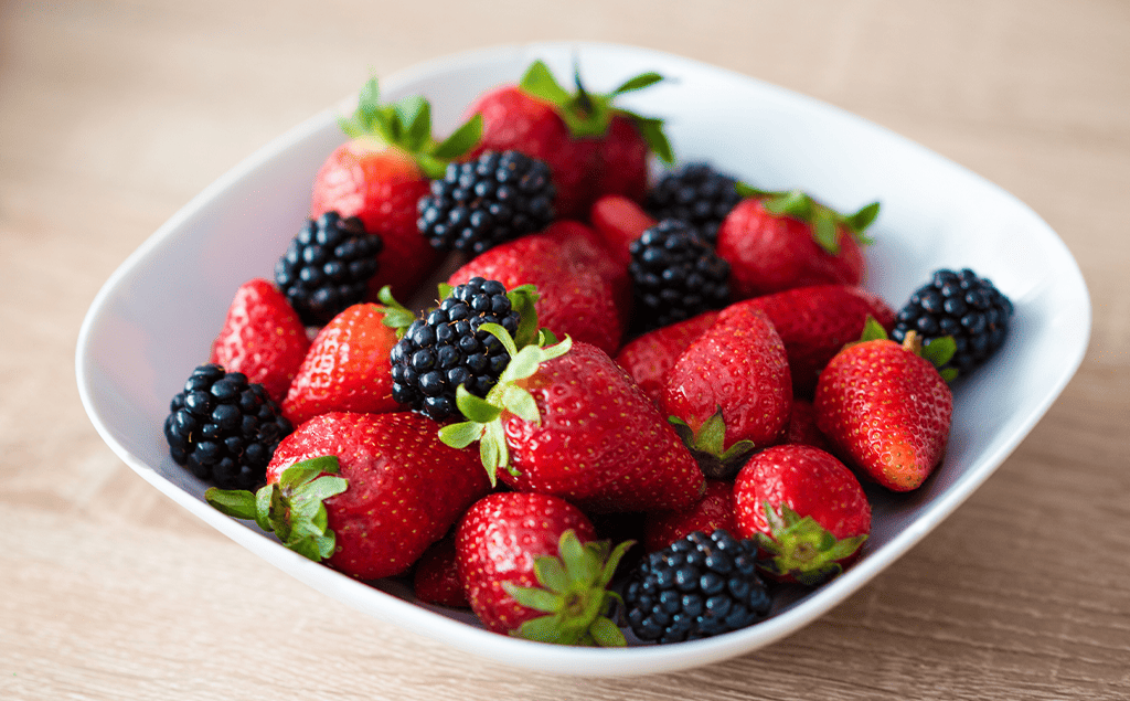 strawberries and blackberries in a white bowl