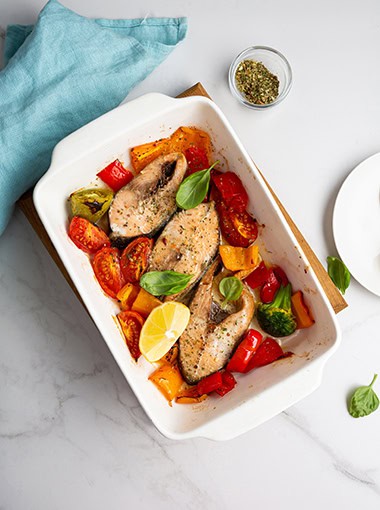 Overhead view of roasted fish with tomatoes in dish