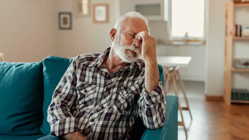 unwell senior man sitting on sofa