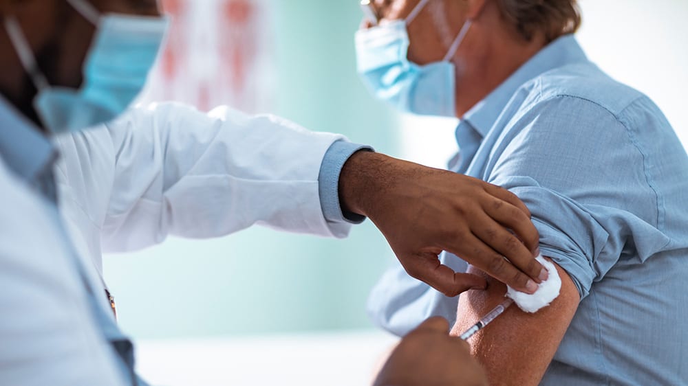 Person wearing a mask receiving a vaccine injection