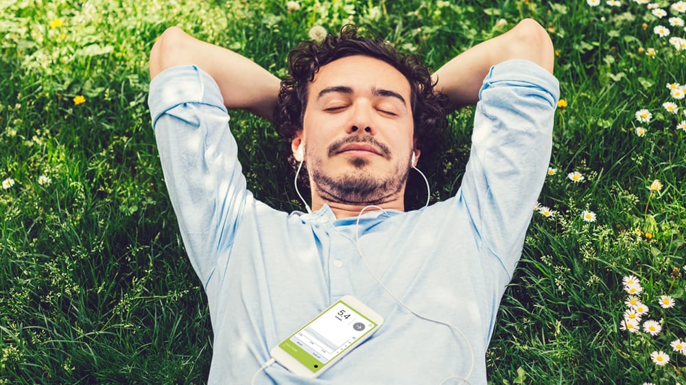 Man relaxing on the grass with arms behind his head